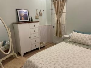a bedroom with a bed and a dresser with a picture on it at Evangeline House in Da Lat