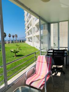 a chair and a piano on a balcony with a view at Primera línea frente al mar, con gran piscina. in Coquimbo