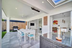 a kitchen and living room with a white table and chairs at WhiteSands in Port Douglas