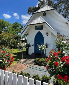 een witte kerk met een blauwe deur en rode bloemen bij The Church at Barrington in Barrington