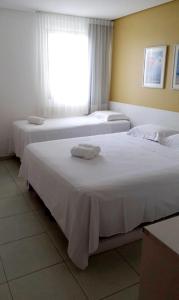 two beds in a hotel room with towels on them at Carneiros Beach Resort - Apto 214D in Tamandaré