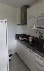a kitchen with white cabinets and a black counter top at Carneiros Beach Resort - Apto 214D in Tamandaré