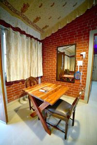una mesa de madera y sillas en una habitación con una pared de ladrillo en Amrit Van Resort, en Jaipur
