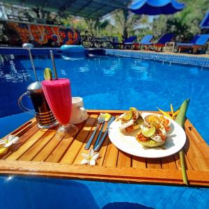 a table with a plate of food next to a swimming pool at Karma Traders Kampot in Kampot
