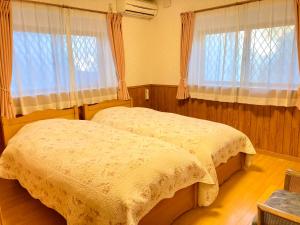 two beds in a bedroom with two windows at Villa Relax in Fujikawaguchiko