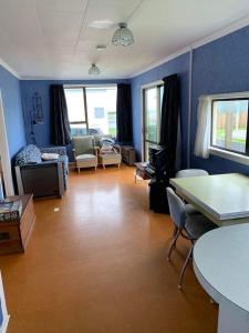 a living room with blue walls and a table and chairs at Urenui Beach Bach in Urenui