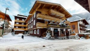 een groot gebouw met sneeuw op de grond bij Hotel Panther'A in Saalbach Hinterglemm