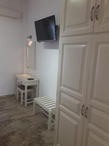 Zimmer mit einer Tür, einem TV und einem Tisch in der Unterkunft Katerina Studios in Paleokastritsa
