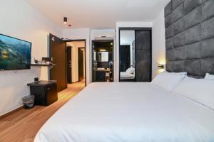 a bedroom with a large white bed and a tv at Selfie's Boutique Hotel in Tiberias