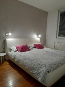 a bedroom with a bed with two pink pillows at ARS VIP Apartment in Novi Sad