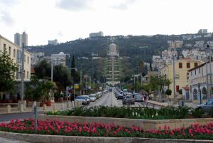 a city street with cars driving down a street with pink flowers at BenGurion 25 Apartment in Haifa