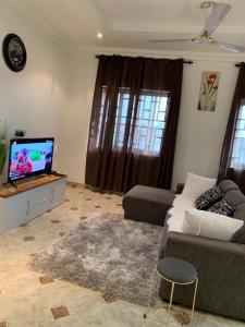 a living room with a couch and a flat screen tv at SUCCESS ROOM Ensuit - East Legon, Adjiringanor in Accra