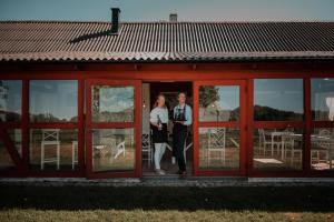 une mariée et un marié debout à l'entrée d'une maison rouge dans l'établissement SOEDER Countryhouse & Kitchen, à Båstad