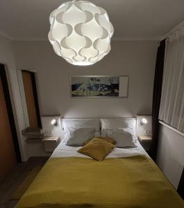 ein Schlafzimmer mit einem Bett mit gelber Decke und einem Kronleuchter in der Unterkunft Südhang FeWo in Murau