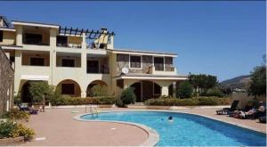 una casa grande con piscina frente a ella en Il Borgo Del Sole en Villasimius