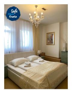 een slaapkamer met een groot wit bed en een kroonluchter bij Hotel Martini Zagreb Hotel and Restaurant in Sesvete