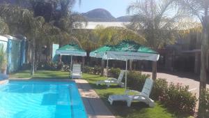 a swimming pool with two chairs and umbrellas next to a house at Palm Valley Inn in Hartbeespoort