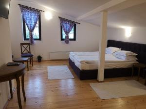 a bedroom with a bed and a table and two windows at Algarte Guest House in Madzhare