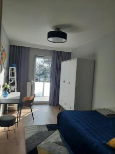 a bedroom with a blue bed and a desk and a window at Luksusowy Apartament Parkowa Olecko in Olecko