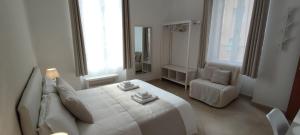 a white bedroom with a large bed and a chair at Nell'Azzurro in Cagliari