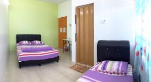 two beds in a room with purple and purple sheets at Ipoh TZY's Homestay in Ipoh