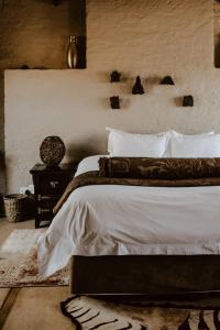 um quarto com uma cama com lençóis brancos e uma mesa em African Leaves Trout Lodge em Dullstroom