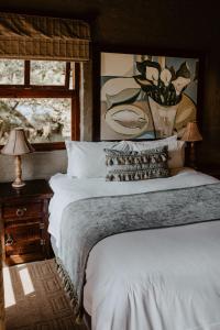 a bedroom with a large white bed with a painting at African Leaves Trout Lodge in Dullstroom