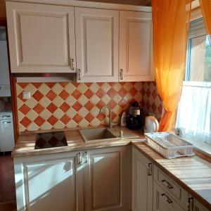 a kitchen with white cabinets and a sink and a window at Mediterrán Vendégház in Nagyatád