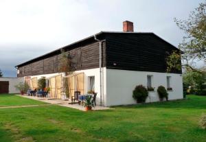 ein großes weißes Haus mit schwarzem Dach in der Unterkunft Wohnung in Mellenthin - a55965 in Mellenthin