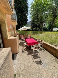 a table and chairs with a red table and an umbrella at T2 + Tout Confort + Terrasse in Aulus-les-Bains