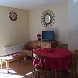 a living room with a table and a television at T2 + Tout Confort + Terrasse in Aulus-les-Bains