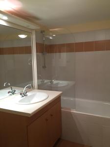 W łazience znajduje się umywalka, wanna i lustro. w obiekcie T2 + Tout Confort + Terrasse w mieście Aulus-les-Bains