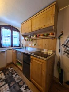 a kitchen with wooden cabinets and a stove top oven at Bilocale Ristrutturato in Madesimo