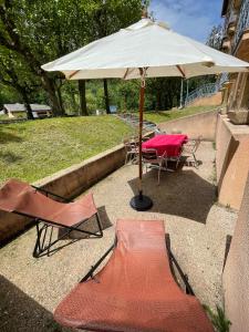 stół i dwa krzesła pod parasolem w obiekcie T2 + Tout Confort + Terrasse w mieście Aulus-les-Bains