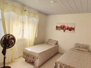 a bedroom with two beds and a window at Isa Natal 2 - Banheiro Privativo in Natal