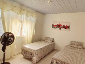 a bedroom with two beds and a window at Casa Petit - Banheiro Exclusivo in Natal
