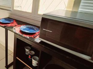 un horno microondas con platos y tazas sobre una mesa en Casa Petit - Banheiro Exclusivo, en Natal