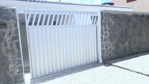 um portão branco em frente a uma parede de pedra em Casa Petit - Banheiro Exclusivo em Natal