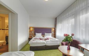 a hotel room with a bed and a vase of flowers at Hotel Da Vinci in Gröbenzell