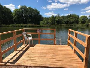 a wooden dock with a chair sitting on top of a lake at Pastourelle in Quarré-les-Tombes