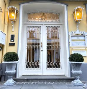 a white door on a building with two plants at Das Hotel Krone in Königswinter