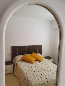 1 dormitorio con 1 cama con 2 almohadas amarillas en APARTAMENTO CON GRAN TERRAZA, PISCINA Y CON VISTAS AL MAR, A SOLO 50 m DE LA PLAYA, en Daimuz