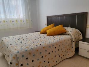 a bedroom with a bed with two yellow pillows at APARTAMENTO CON GRAN TERRAZA, PISCINA Y CON VISTAS AL MAR, A SOLO 50 m DE LA PLAYA in Daimuz