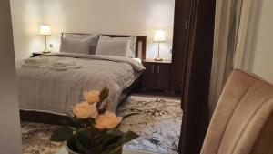 - une chambre avec un lit et un vase avec des fleurs dans l'établissement IRIS Apartments, à Bitola