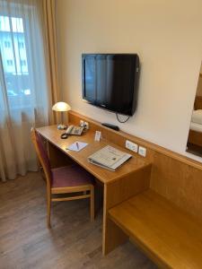 um quarto com uma secretária e uma televisão na parede em Hotel garni St.Georg em Sankt Wolfgang