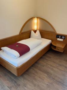 a bed with a wooden headboard in a room at Hotel garni St.Georg in Sankt Wolfgang