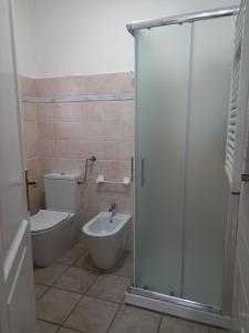 La salle de bains est pourvue de toilettes, d'un lavabo et d'une douche. dans l'établissement Appartamento Piano Terra Residence Geranium Beach, à San Teodoro