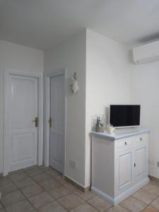 Cette chambre blanche dispose d'une télévision sur un comptoir et d'une porte. dans l'établissement Appartamento Piano Terra Residence Geranium Beach, à San Teodoro