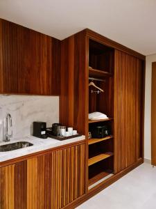 uma cozinha com armários de madeira, um lavatório e um balcão em Flat Deluxe no centro de Pipa em Pipa