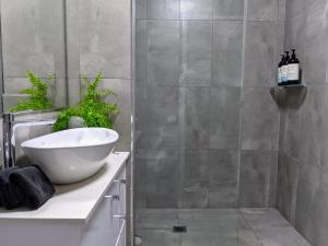 uma casa de banho com um chuveiro, um lavatório branco e uma banheira em The Botanical 304 em Albury